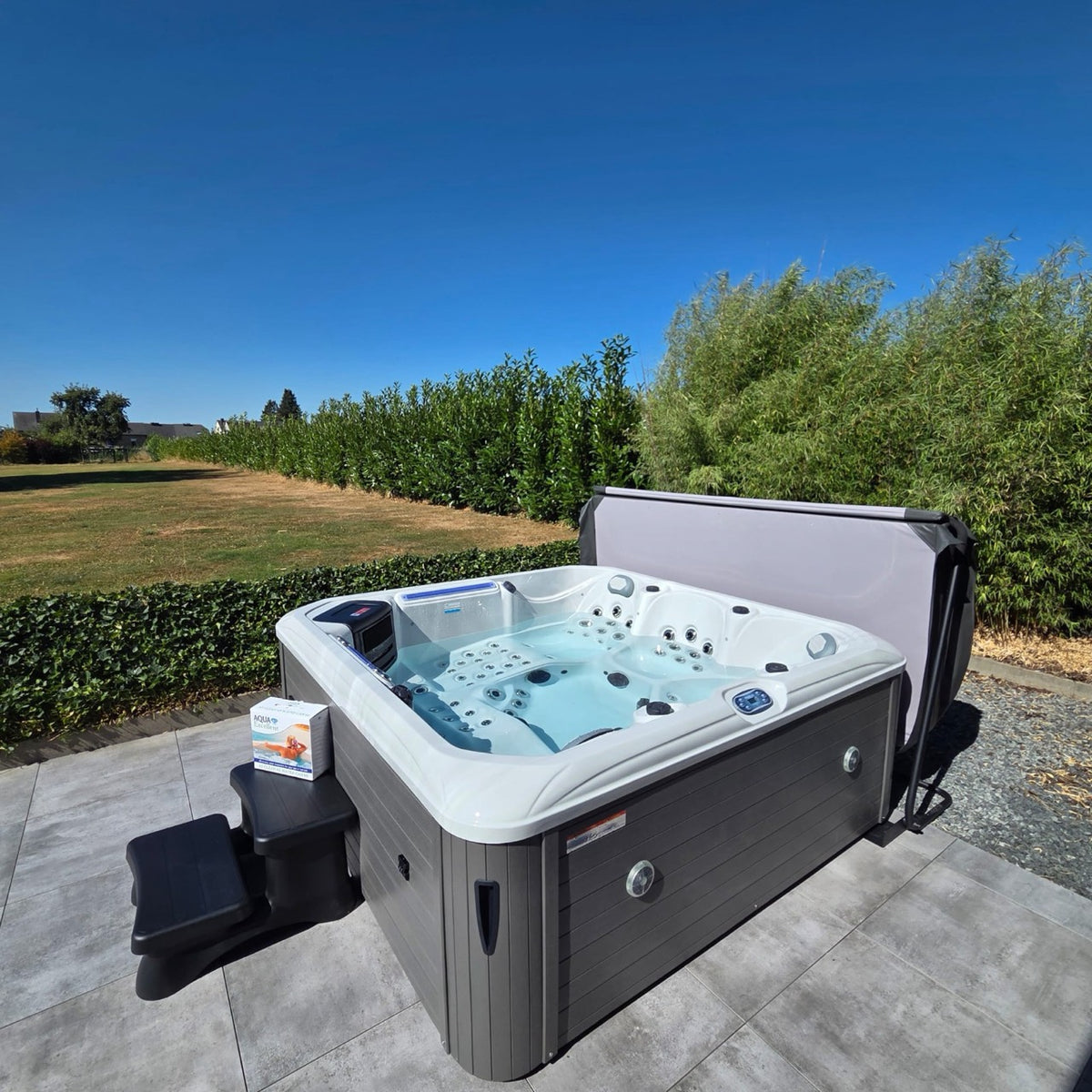 Spa blanc installé sur une terrasse, devant une haie de bambous
