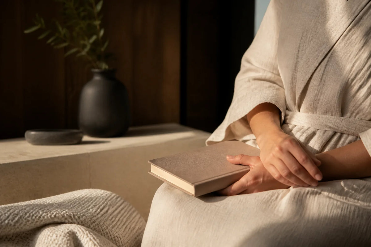 Nero 210X - Indoor-Sauna für 4-5 Personen im Abendlicht mit Bademantel und Buch für den Übergang zur Ruhe